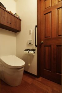 【1F　トイレ】 タンクレストイレ　吊戸棚：造作家具　壁：漆喰仕上げ　