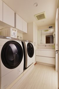 洗濯機が２台置けるように洗濯機と洗面台の位置を逆転。吊戸棚も取り付けて収納もばっちり。洗面横のPSのデッドスペースを活かし収納を増やしました。