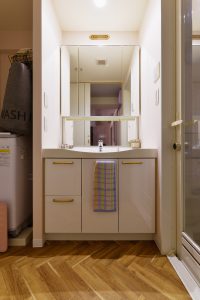 洗面室：洗面台は既存を活かし、リビングとの雰囲気を合せるために床にヘリンボーン調のクッションフロアを貼りました。