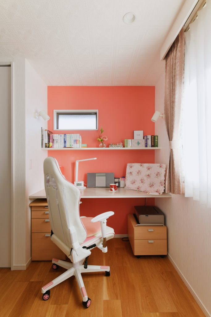 寝室の一角に作った奥様の書斎スペース： 奥様お気に入りのサーモンピンクのアクセントクロスが映えます。
