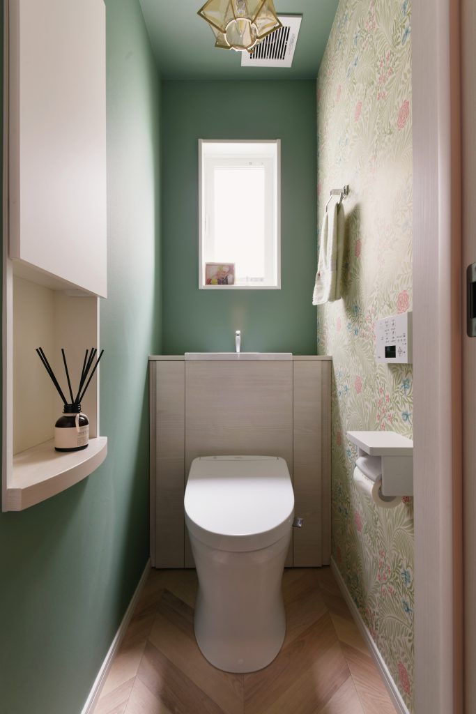 １階トイレ：２階とうってかわってグリーンの落ち着いた空間。アクセントクロスはウィリアムモリスの柄です。
