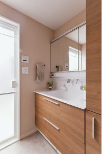 洗面室は木目調の扉カラーと馴染みの良い、落ち着いたベージュカラーのクロスを選択。一面アクセントではなく、室内全体の色味を揃えることでより温かみのある空間になりました。