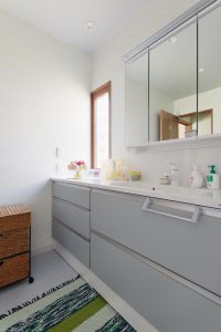1F洗面：面材はグレイッシュグリーンという色を採用。床や壁も合わせてパステルトーンでまとめています。